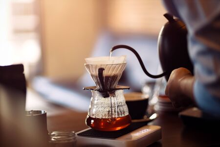 barista pouring boiling water from kettle to drip coffee maker.の写真素材