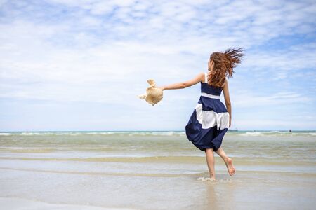 Woman barefoot walking on summer along wave of sea water and sand on the beach. の写真素材