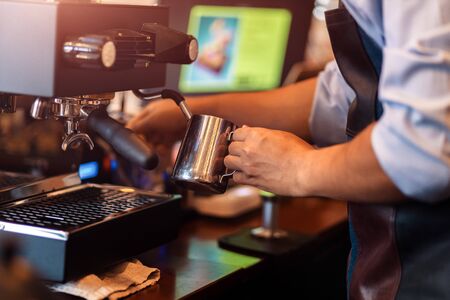 Barista steaming milk in the pitcher with coffee machine for  preparing to make latte art.の写真素材