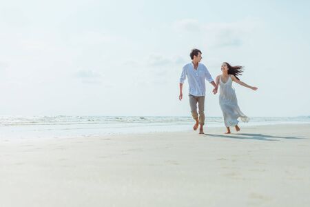 Romantic couple holding hands running and walking on beach. Man and woman in love.の写真素材