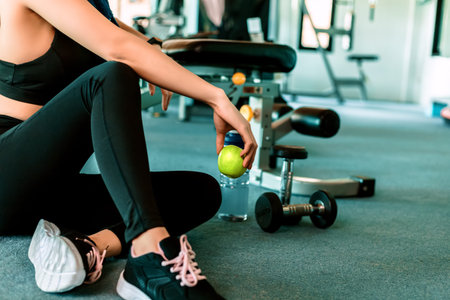 Woman exercise in gym fitness breaking and relax. hand  holding apple fruit after training sport and...