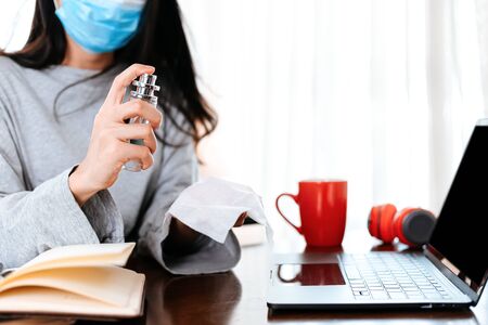 Woman cleaning her hands with a tissue.  Business woman working from home wearing protective mask.  の写真素材