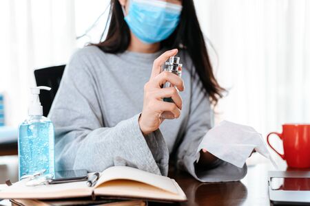 Woman cleaning her hands with a tissue.  Business woman working from home wearing protective mask.  の写真素材