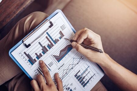 Businessman hold pen and working calculate data. document graph chart and report marketing. Business office concept.の写真素材