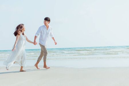 Romantic couple holding hands running and walking on beach. Man and woman in love.の写真素材