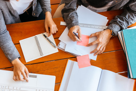 High school or college students  group catching up workbook and learning tutoring on desk and...
