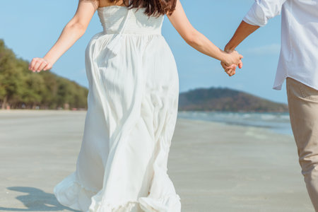 Romantic couple holding hands running and walking on beach. Man and woman in love. People travel...