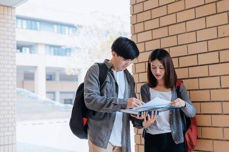 Students stand to read a book together on the campus. Education concept.の写真素材