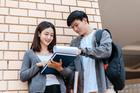 Students stand to read a book together on the campus. Education concept.の写真素材