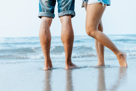 Legs of  couple stand together on beach. Man and woman in love.