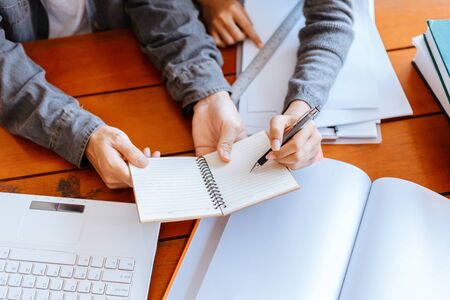 High school or college students  group catching up workbook and learning tutoring on desk and reading, doing homework, lesson practice preparing exam.
studying and reading together in library education concepts. Education concept.の写真素材