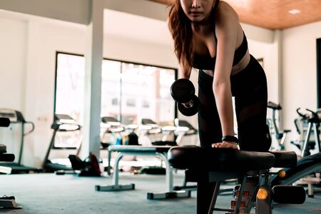 Fitness girl lifting dumbbell in fitness gym. Fitness workout and muscle concept.の写真素材