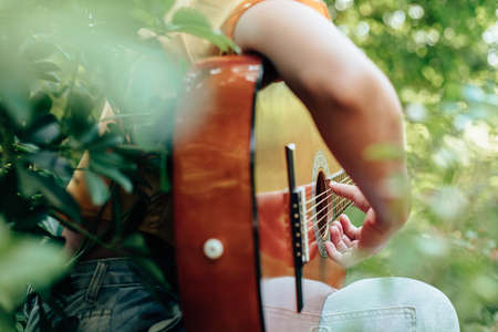 woman's hands playing acoustic guitar have fun outdoor, close up.の写真素材