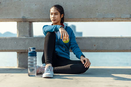 Healthy woman hold apple fruit and sitting on the ground.の写真素材