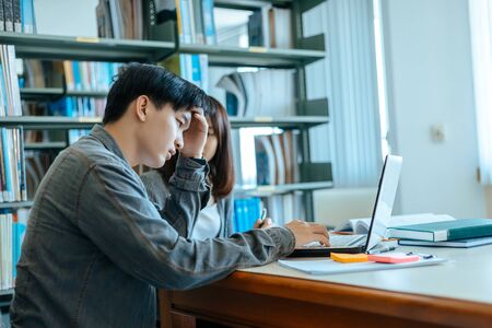 Students have headache, stress, worry about reading in the library. Education concept.の写真素材