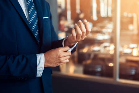 businessman wearing business suit fasten cufflink or button on sleeve of classic jacket and factory background.の写真素材
