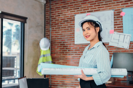Portrait Asian engineer woman hold engineer drawing design blue print at room site construction.