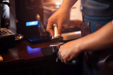 Barista holding portafilter and coffee tamper making  coffee at cafe.の写真素材