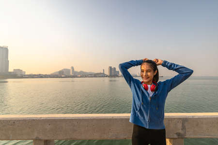 Young sport woman tying hair before her running and city background in the morning.の写真素材