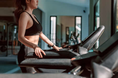 Young woman running treadmill at gym for cardio. Fitness workout concept.の写真素材