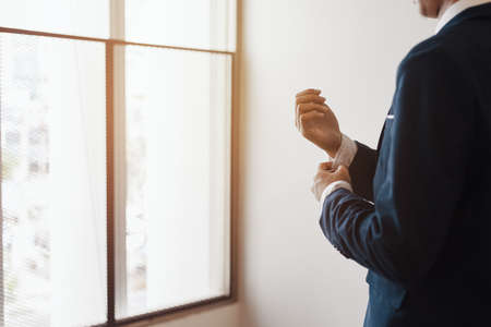 businessman wearing business suit fasten cufflink or button on sleeve of classic jacket and factory background.の写真素材
