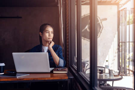 Young woman sitting at coffee shop and  seeing out side windows.の写真素材