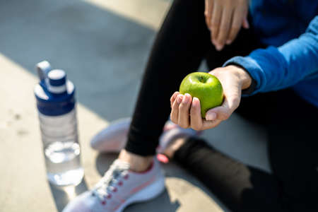 Healthy woman hold apple fruit and sitting on the ground.の写真素材