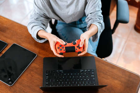 Funny Young woman wearing earphones playing computer game on laptop with joypad.の写真素材