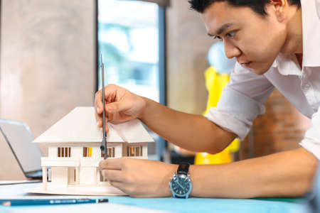 Engineering hands hold vernier caliper working and checking house model scale between meeting with businessman and businesswoman.の写真素材