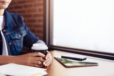 Young girl and hot cup of coffee. Book, pen and tablet on thetable.