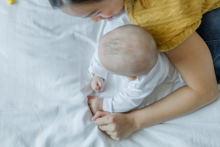 Happy mom and baby playing together on the bed at home . family love concept.