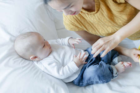 Happy mom and baby playing together on the bed at home . family love concept.の写真素材