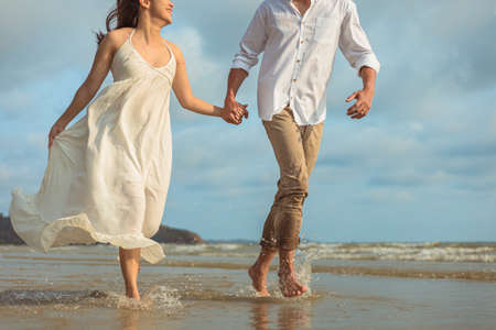 Young couple holding hands and running on the beach.の写真素材