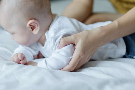 Happy mom and baby playing together on the bed at home . family love concept.の写真素材