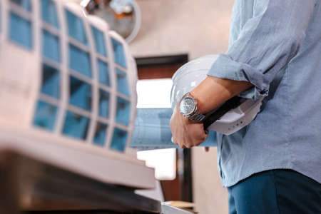 engineer hold engineer drawing design blueprints and safety helmet in room at site construction.の写真素材