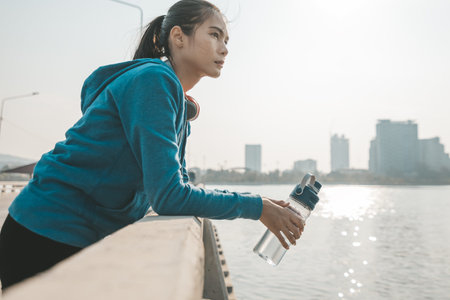 woman athlete thirsty takes a break. she hold water bottle after running.