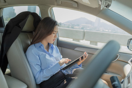 Businesswoman inside a car using a tablet for working.