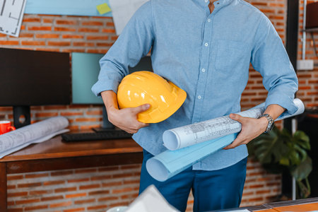 engineer hold engineer drawing design blueprints and safety helmet in room at site construction....