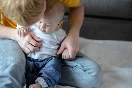 Happy father playing with adorable baby in the room at home.