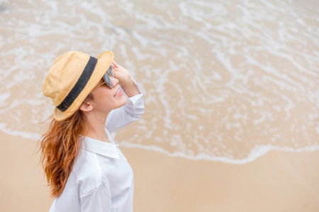 smiling young woman in sun hat and waring sun glasses on the  beach. summer, holidays, vacation, travel conceptの写真素材