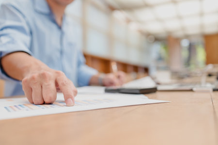 Businessman hands point paper graph and checking document data calculator for calculate budget accountancy. finance and accounting conceptの写真素材