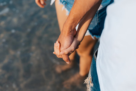 Couple of lovers holding hands on the beach in the morning.  Newlywed couple on a romantic vacationの写真素材