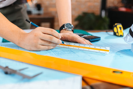engineers holding a pen pointing to a building and  drawing outlay construction plan as guide for...