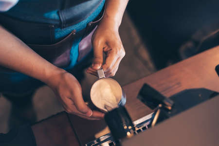 Barista heats milk steam for making lattes at coffee shop.の写真素材