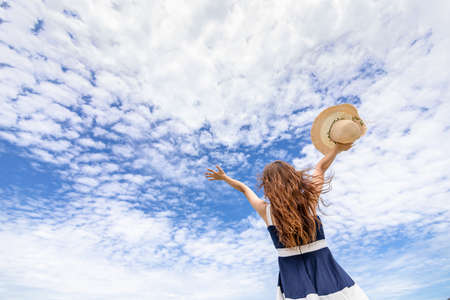 Young woman raise a hat in the sky on the beach. Summer vocation island.の写真素材