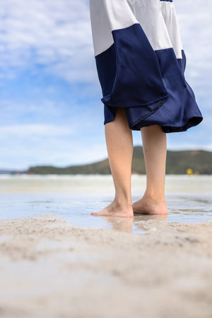Woman barefoot walking on summer along wave of sea water and sand on the beach.