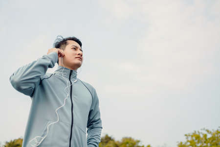 Young sport man jogging and listening music in the park.の写真素材