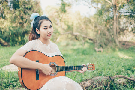 Girl playing guitar in the forest. Music hobby and picnic concept.の写真素材
