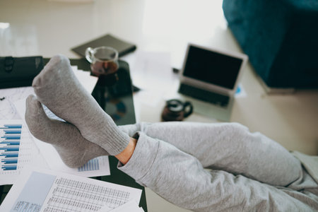 Foot of Young Businessman on the desk working at home with paper graph and data. Business and...