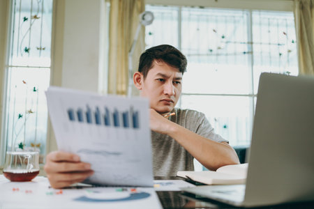 Young Businessman working at home with paper graph and data. Business and freelance concept.